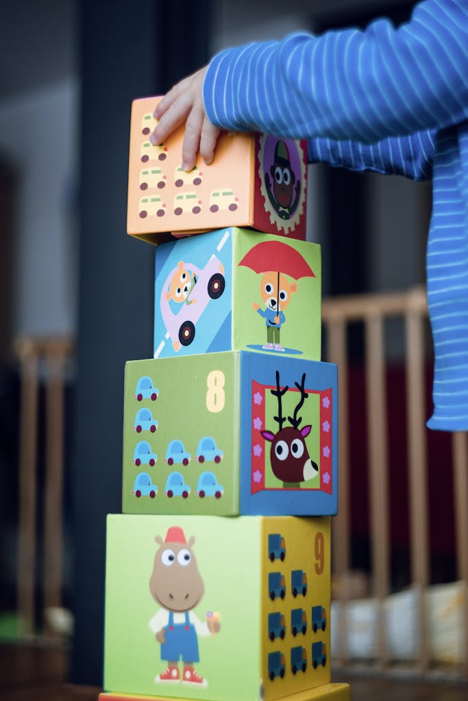 A child playing indoors, stacking colorful wooden toy blocks with joyful illustrations.